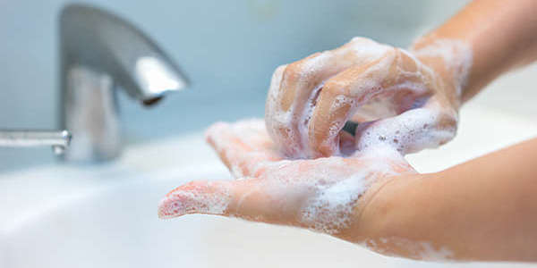 Close-up of a woman's hands washing at the bathroom sink.