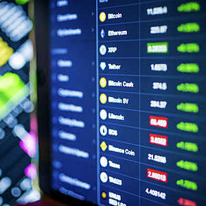 Cryptocurrency and oil exchange prices displayed on a large stock market trading screen.