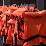 Vanishing perspective of orange lifejackets on black hangers.
