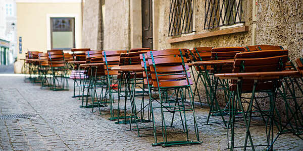 Rows of tables with folded chairs outside a café in a deserted street.